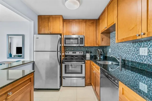 a kitchen with stainless steel appliances granite countertop a refrigerator a stove and a sink
