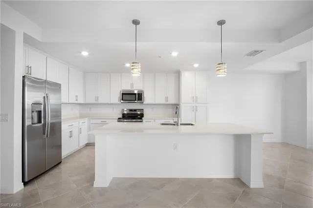 a kitchen with kitchen island a refrigerator a sink stainless steel appliances and cabinets