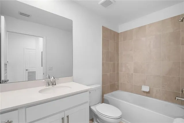 a bathroom with a bathtub shower sink vanity mirror and toilet