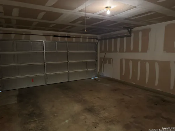 an empty room with a chandelier fan and windows