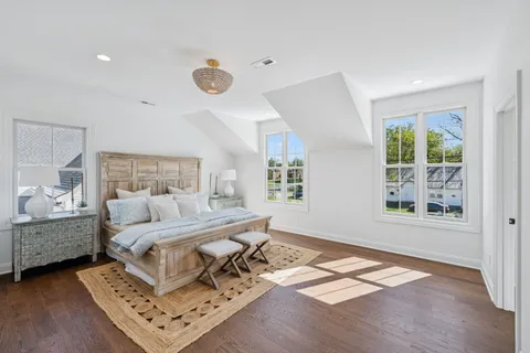 a bedroom with a bed window and walk in closet with wooden floor