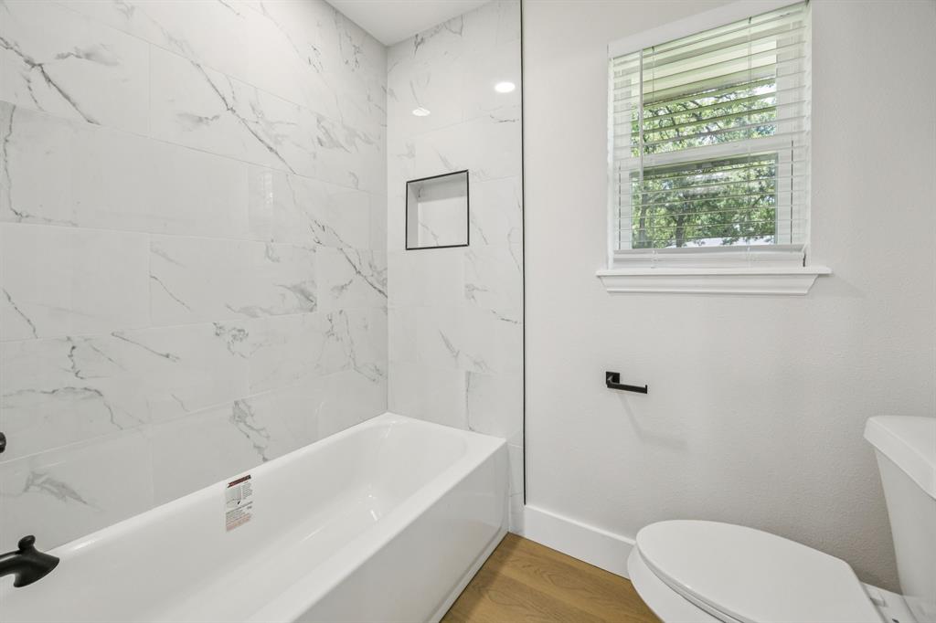 37 Devonshire Bedford, TX 76021 - Photo 29 of 39 a bath room with a toilet a bath tub and a shower