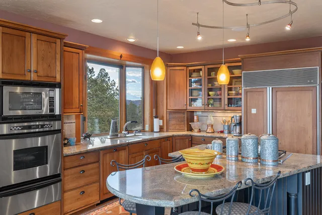 a kitchen with granite countertop a stove a sink a refrigerator dining table and chairs