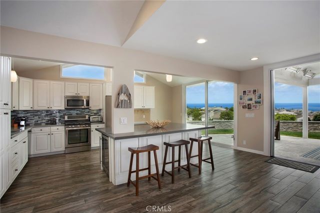 a kitchen with stainless steel appliances wooden floor and a refrigerator