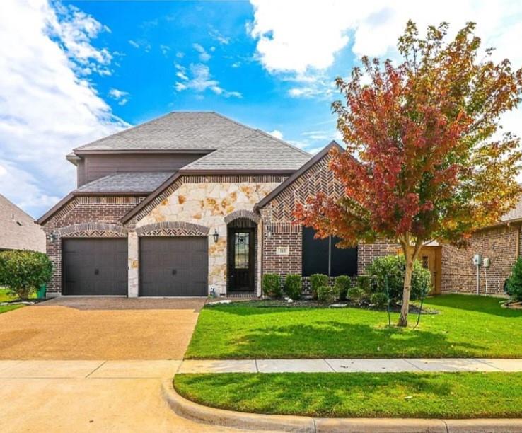 a view of a house with a small yard and a large tree