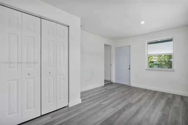 a view of an empty room with closet and a window