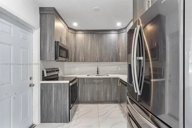 a kitchen with stainless steel appliances granite countertop a refrigerator and a sink