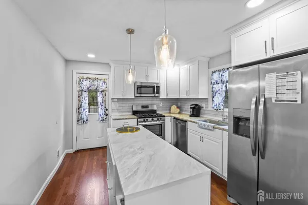 a kitchen with refrigerator a microwave a stove and white cabinets with wooden floor