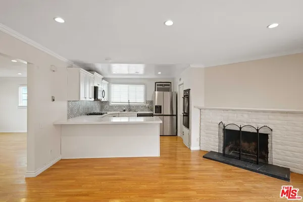 a view of kitchen with stainless steel appliances wooden floor and window