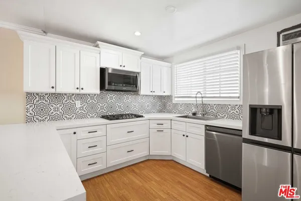 a kitchen with granite countertop white cabinets and stainless steel appliances