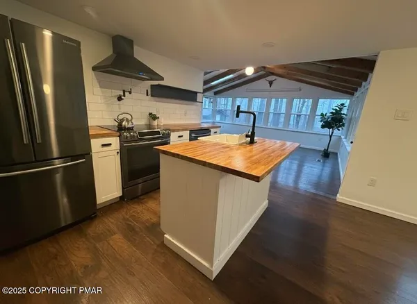 a kitchen with stainless steel appliances granite countertop a refrigerator a stove and a wooden floors