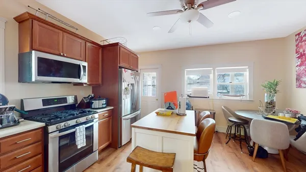 a kitchen with stainless steel appliances granite countertop a stove a sink dishwasher a dining table and chair with wooden floor