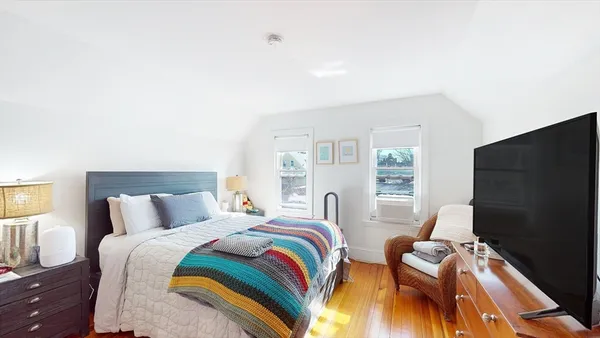 a bedroom with a bed and a flat tv screen on dresser