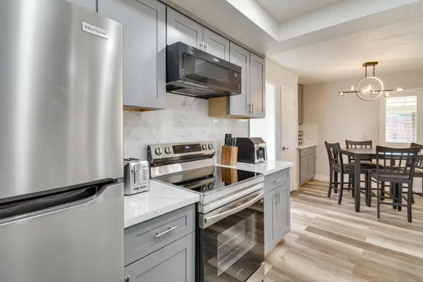 a kitchen with stainless steel appliances a stove a sink and white cabinets