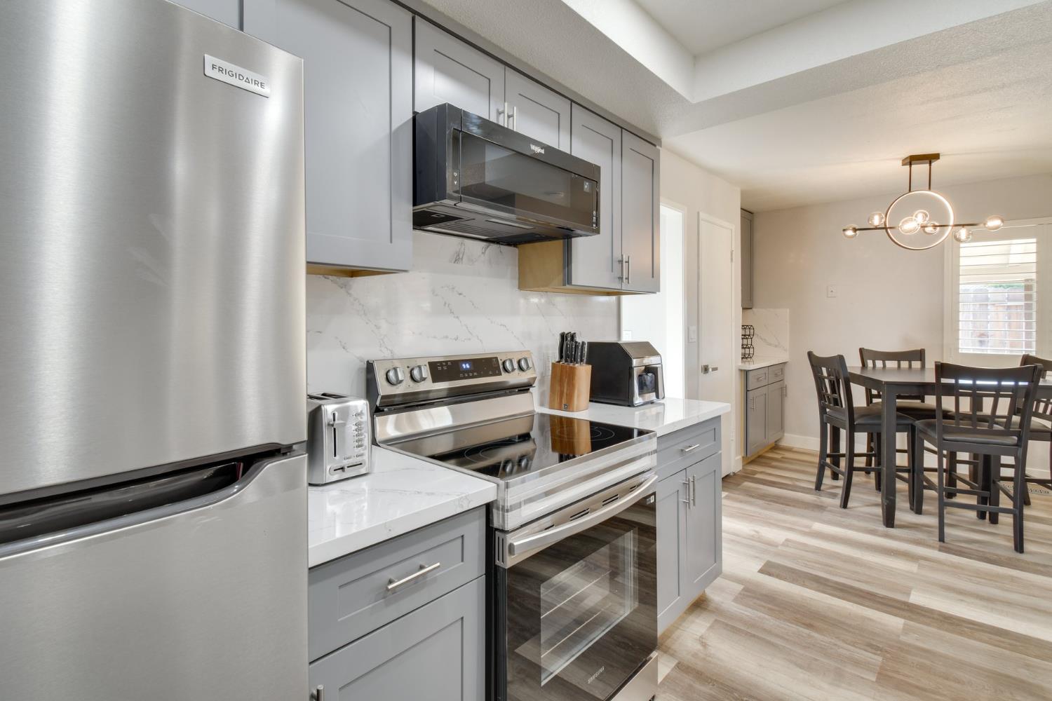 6034 Country Club Place Merced, CA 95340 - Photo 6 of 16 a kitchen with stainless steel appliances a stove a sink and white cabinets