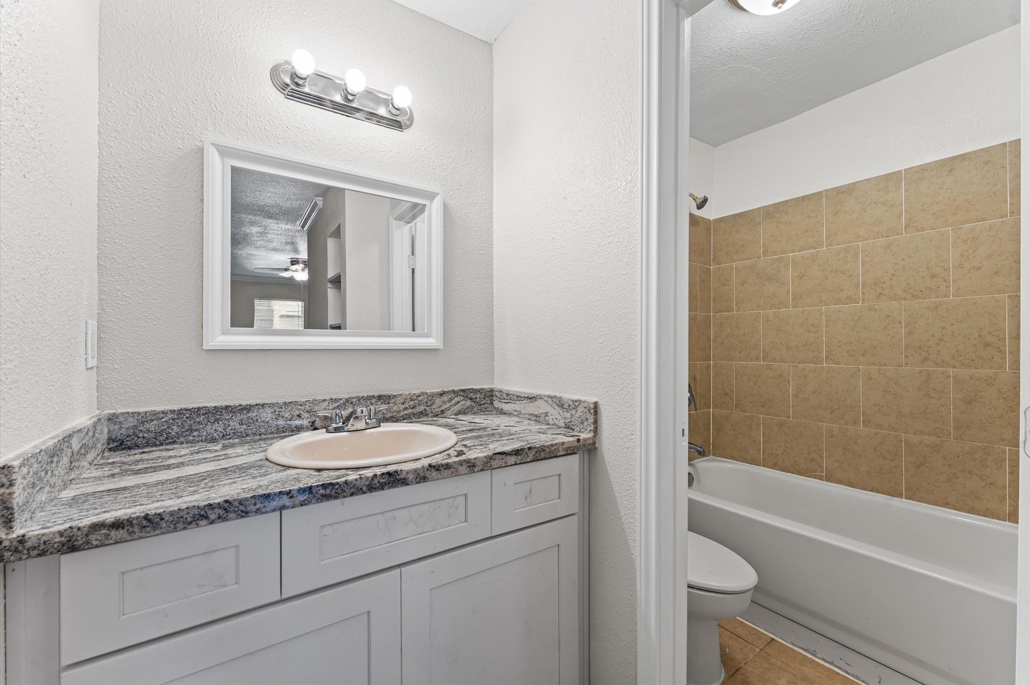 6161 Reims Road, Unit 1006 Houston, TX 77036 - Photo 9 of 19 a bathroom with a granite countertop sink a toilet and bathtub