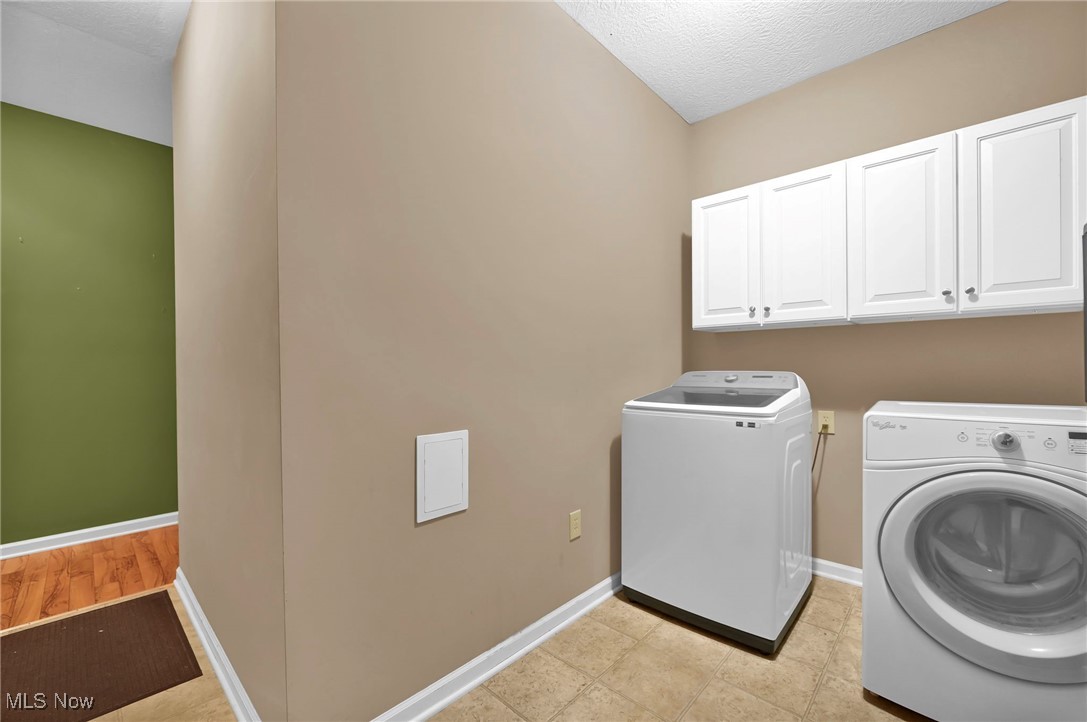 2690 Mayfair Road Akron, OH 44312 - Photo 25 of 31 Laundry area off three car garage featuring washer and dryer, a mud room textured ceiling, and cabinet space