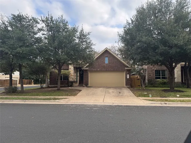 a view of the house with a yard and large trees