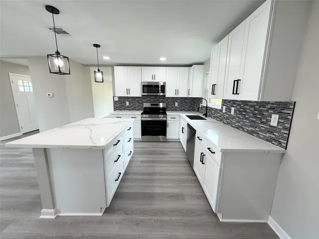 a large kitchen with a stove top oven and white cabinets