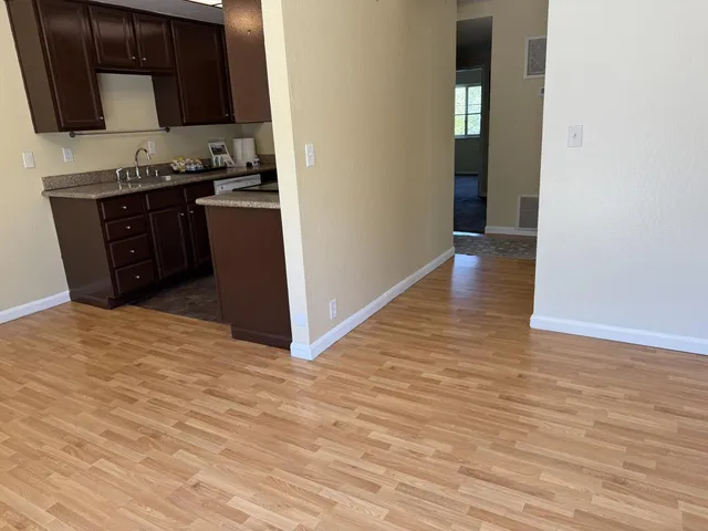 a view of a kitchen with stainless steel appliances wooden floor and cabinets
