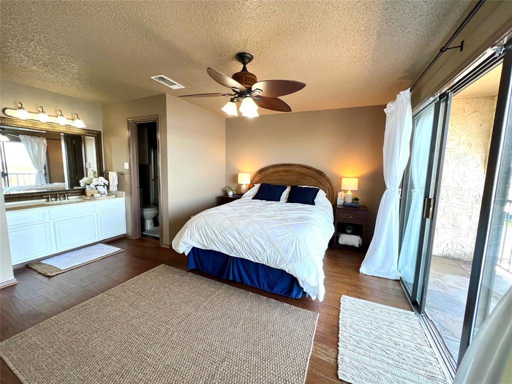 3123 Hells Gate Loop, Unit 45 Strawn, TX 76475 - Photo 15 of 30 a bedroom with a bed lamps and a large mirror on the dresser