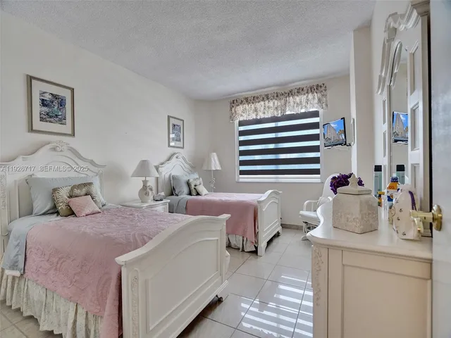a bedroom with two beds and a large mirror next to a window