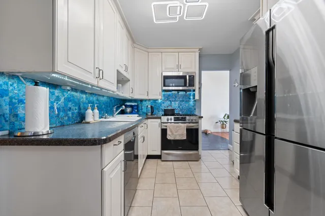 a kitchen with stainless steel appliances granite countertop a refrigerator a sink a stove a microwave and island