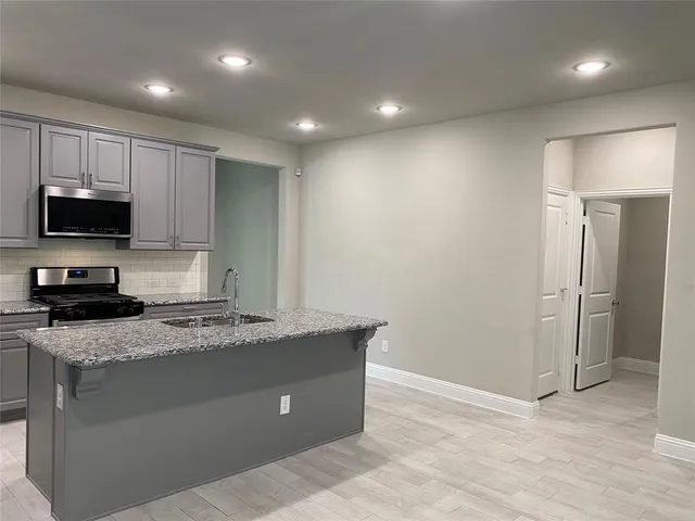 a kitchen with granite countertop a stove a sink and a microwave