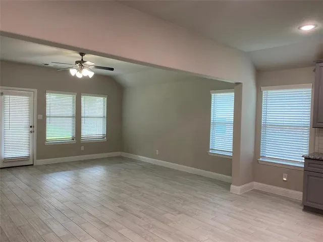 a view of an empty room with a window and wooden floor