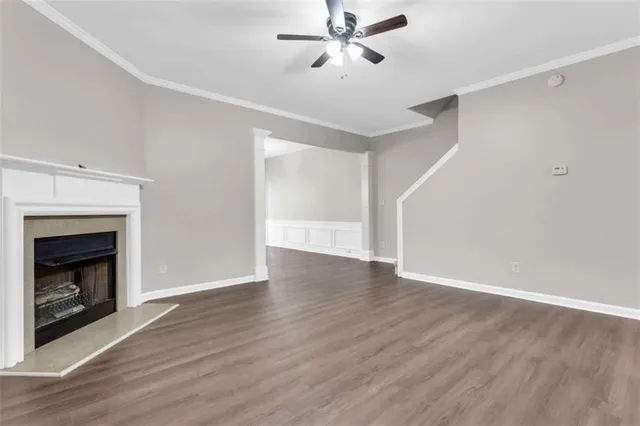a view of an empty room with wooden floor fireplace and a window