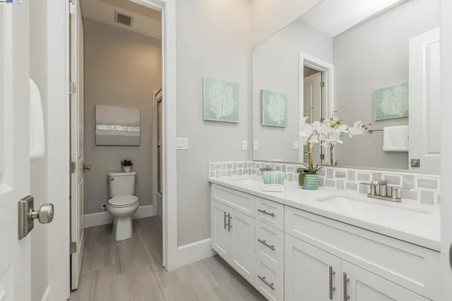 a bathroom with a granite countertop toilet sink and mirror