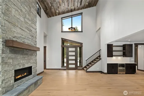 a view of an empty room with wooden floor fireplace and a window