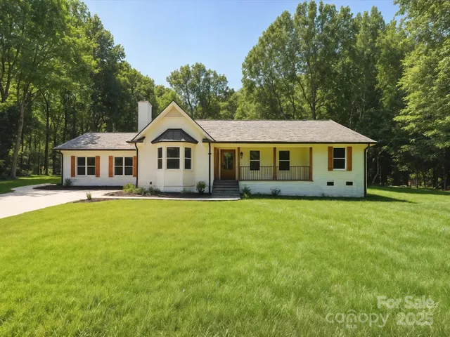 a view of a big house with a big yard and large trees