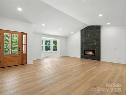 a view of an empty room with wooden floor and a fireplace