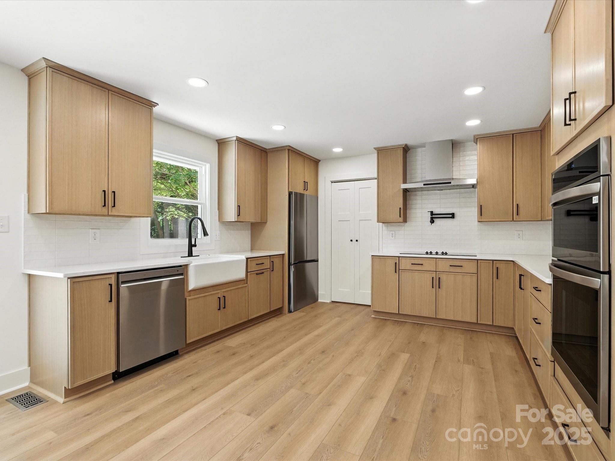 3303 Reid Circle Monroe, NC 28112 - Photo 8 of 44 a large kitchen with a stove a sink dishwasher a refrigerator and white cabinets with wooden floor