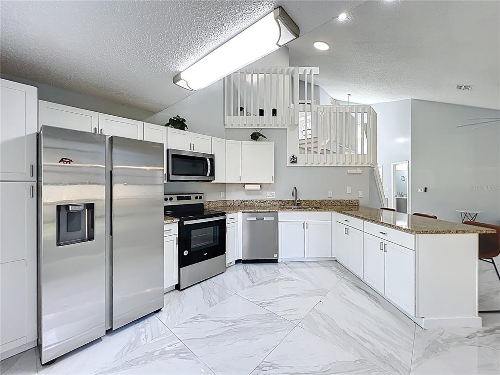 622 Anhinga Road Winter Springs, FL 32708 - Photo 12 of 53 a large kitchen with stainless steel appliances kitchen island granite countertop a refrigerator a stove a sink and white cabinets with wooden floor