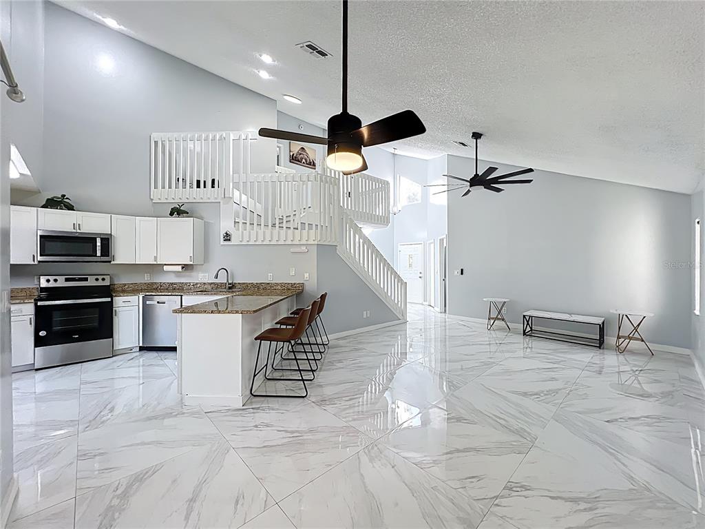 622 Anhinga Road Winter Springs, FL 32708 - Photo 10 of 53 a kitchen with stainless steel appliances kitchen island granite countertop a stove a sink and a refrigerator