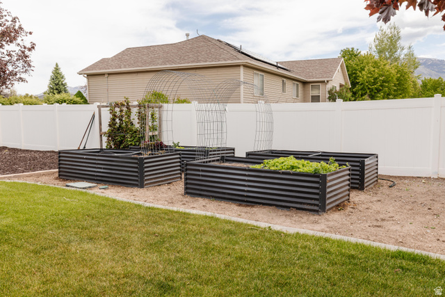 972 West 2840th Street South Logan, UT 84321 - Photo 41 of 46 Backyard garden area featuring four raised planter beds, a white privacy fence, and a manicured lawn