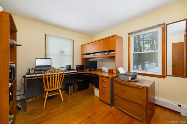 a work room with furniture a flat screen computer and a window