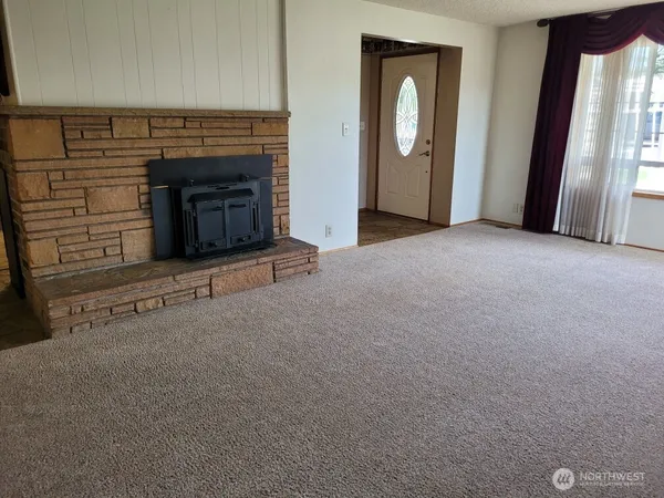 a view of an empty room with window and fire place
