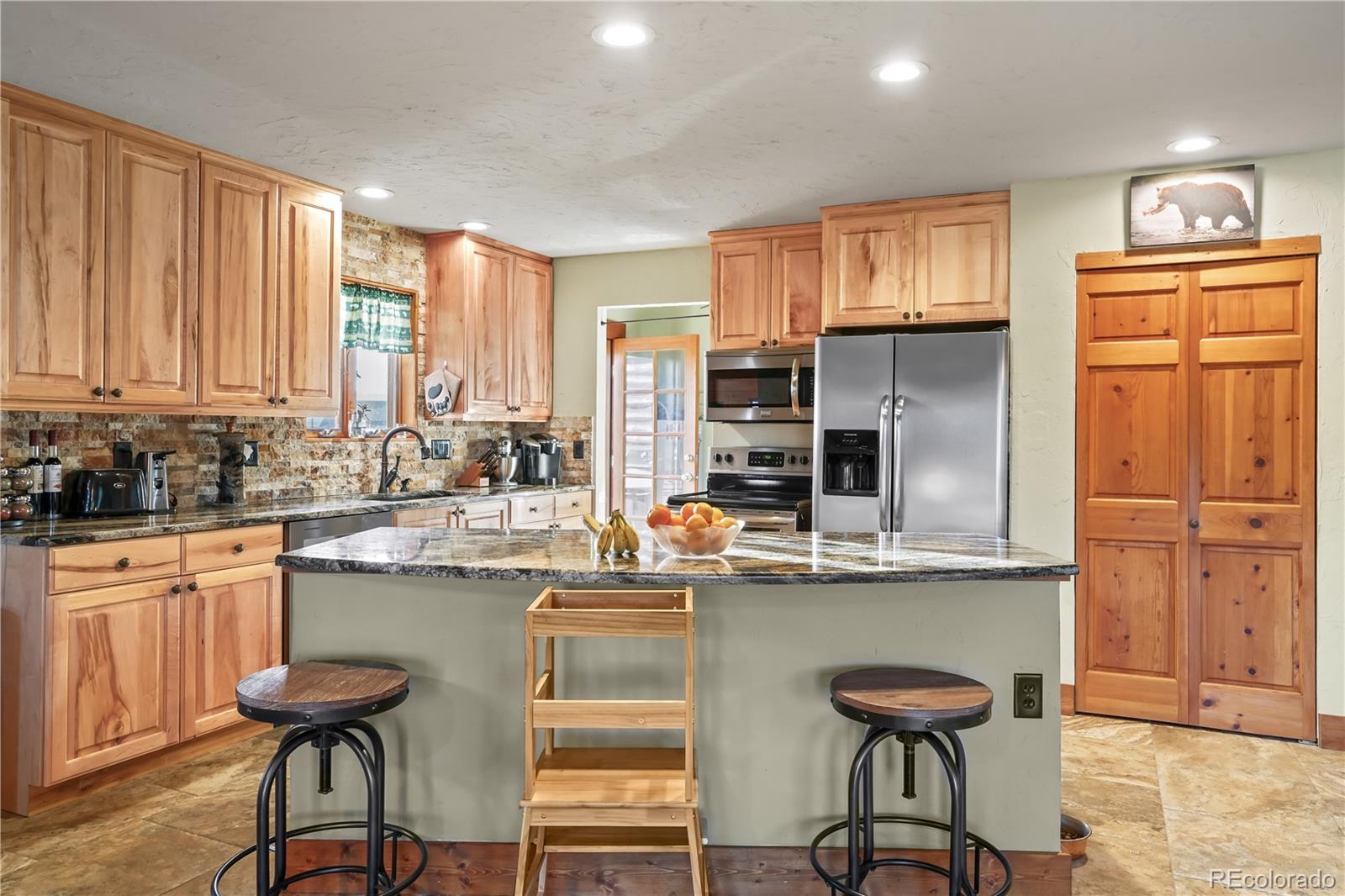 115 County Road 1014 Silverthorne, CO 80498 - Photo 3 of 20 a kitchen with stainless steel appliances kitchen island granite countertop a table chairs in it and wooden floors