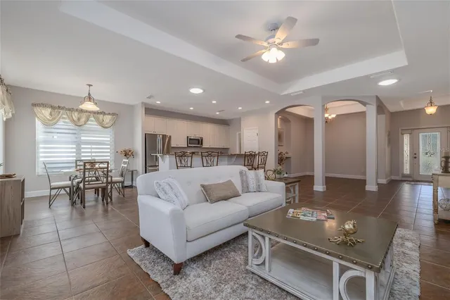 a living room with furniture kitchen view and a chandelier