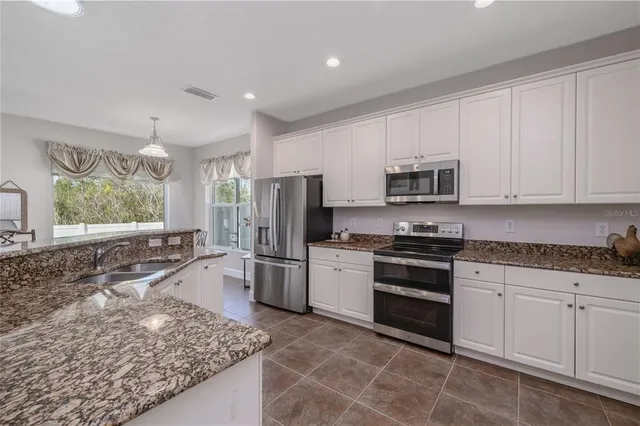 a kitchen with stainless steel appliances granite countertop a stove a sink and a microwave