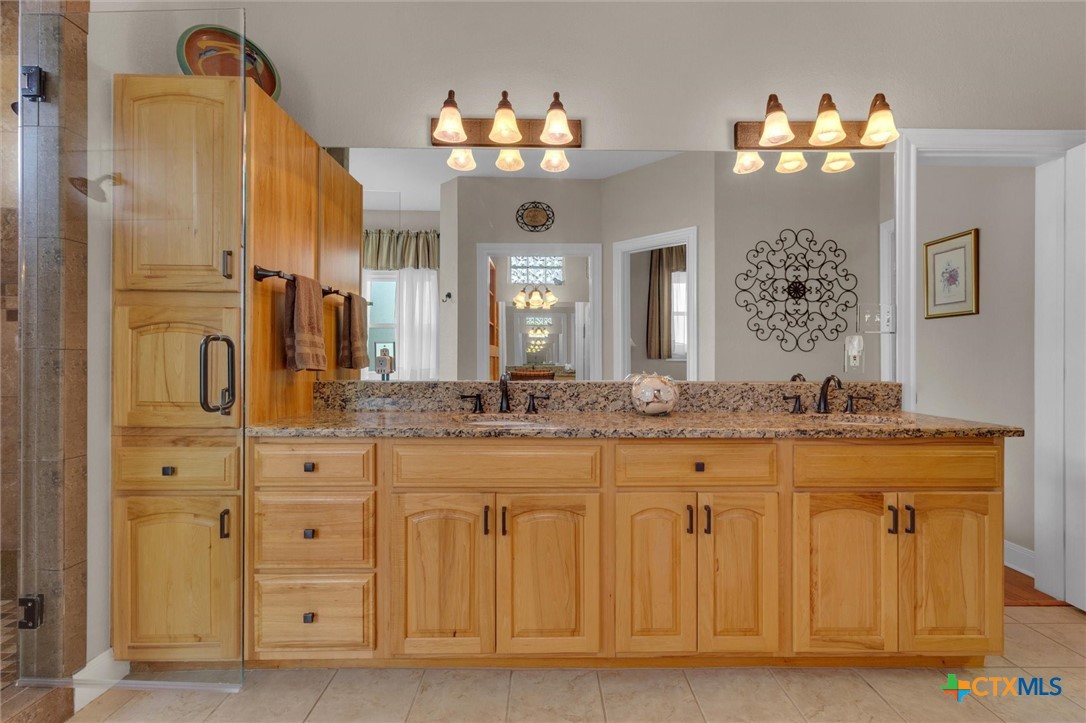 2235 Summit Ridge San Marcos, TX 78666 - Photo 22 of 38 a bathroom with a granite countertop sink a large mirror and a shower