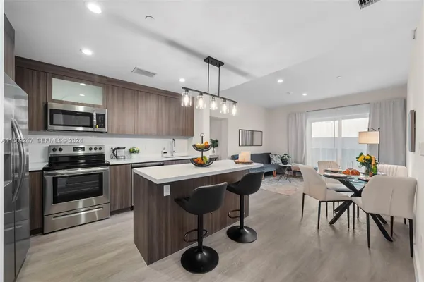 a kitchen with stainless steel appliances granite countertop a table chairs sink refrigerator and microwave
