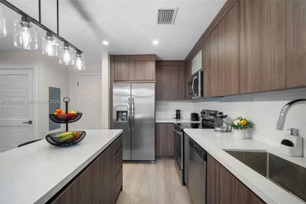 a kitchen with stainless steel appliances kitchen island granite countertop a sink refrigerator and cabinets