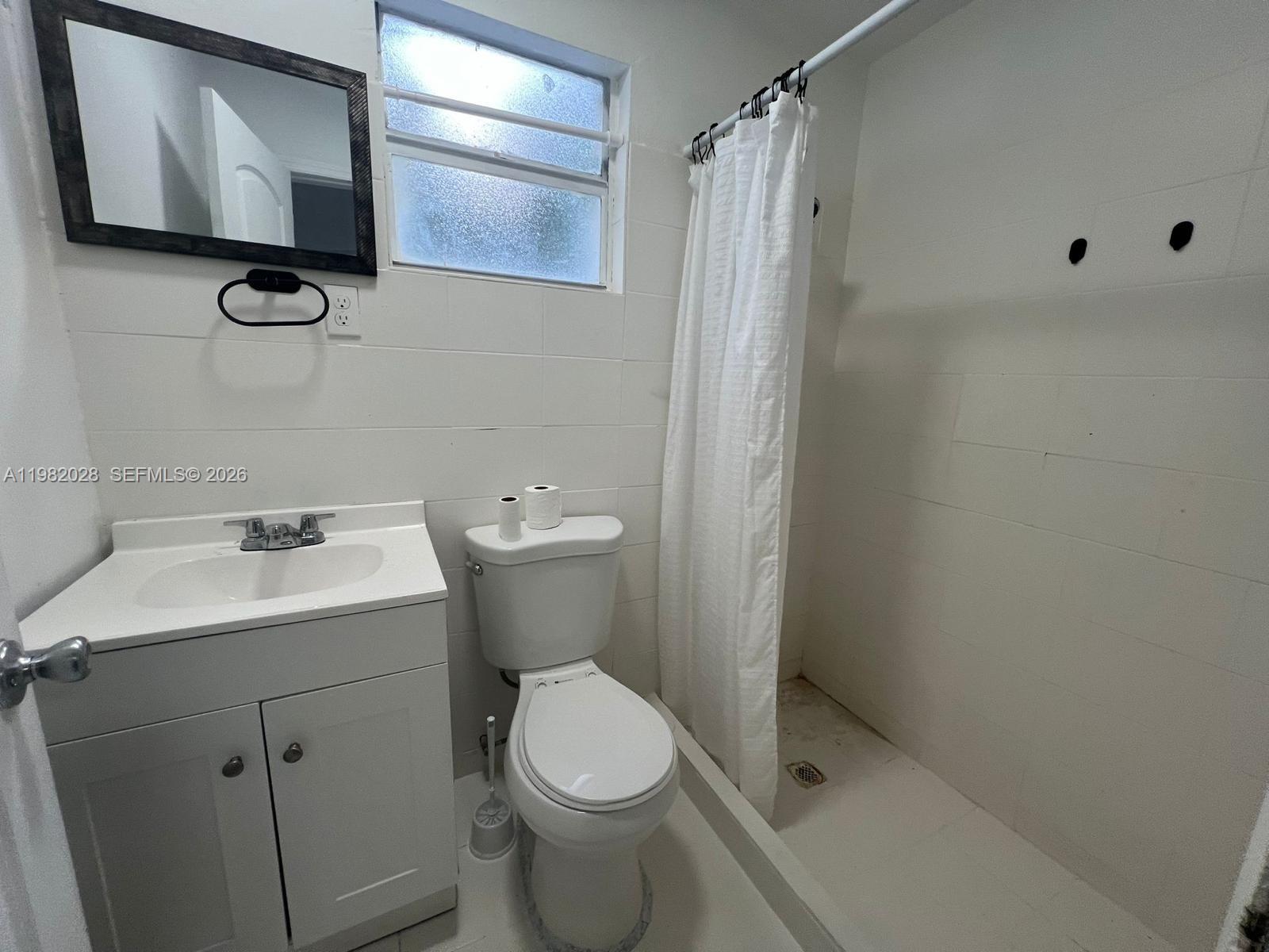 1053 Northeast 149th Street Miami, FL 33161 - Photo 4 of 13 a bathroom with a toilet sink and mirror