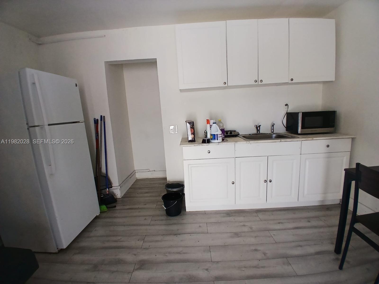 1053 Northeast 149th Street Miami, FL 33161 - Photo 5 of 13 a kitchen with stainless steel appliances white cabinets and wooden floors