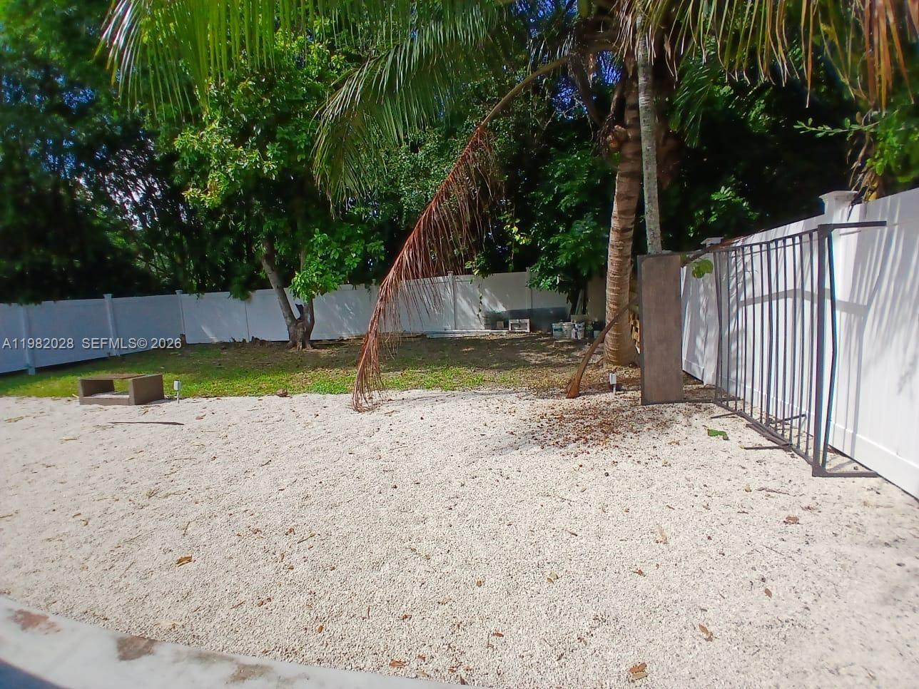 1053 Northeast 149th Street Miami, FL 33161 - Photo 9 of 13 a view of a backyard with large trees and wooden fence