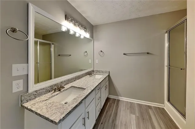 a bathroom with a granite countertop sink a mirror and shower